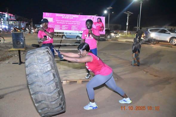 Séance de fitness plein air du CFC en soirée : le groupe en maillots roses avec la banderole de l'événement